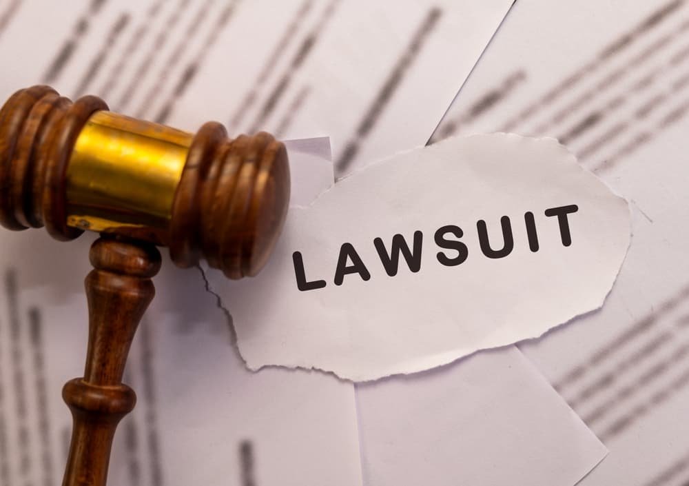 Wooden gavel and torn paper with "Lawsuit" text.