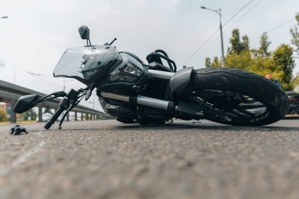 Motocicleta caída en la carretera después de un accidente, representando disputas de responsabilidad y prejuicio contra motociclistas en Florida