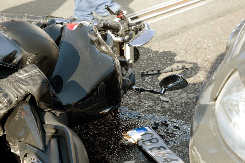 Motorcycle lying on the ground next to a car after a collision, illustrating liability disputes and potential bias against riders in Florida injury claims