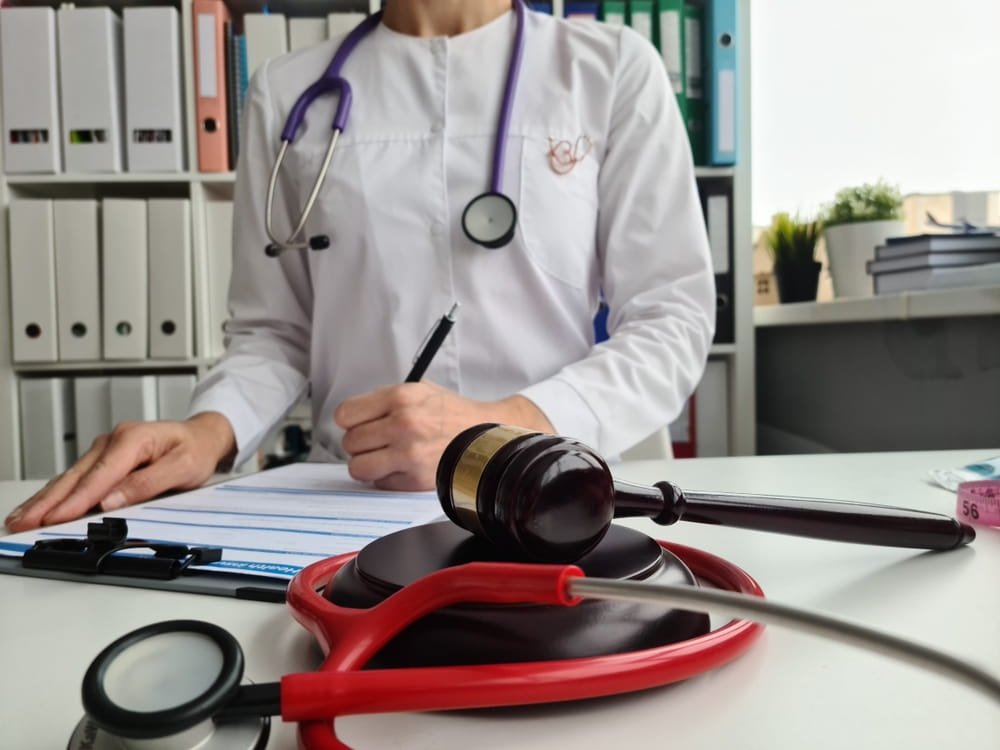 Médico revisando documentos junto a un mazo judicial representando el proceso legal en casos de negligencia médica en Florida