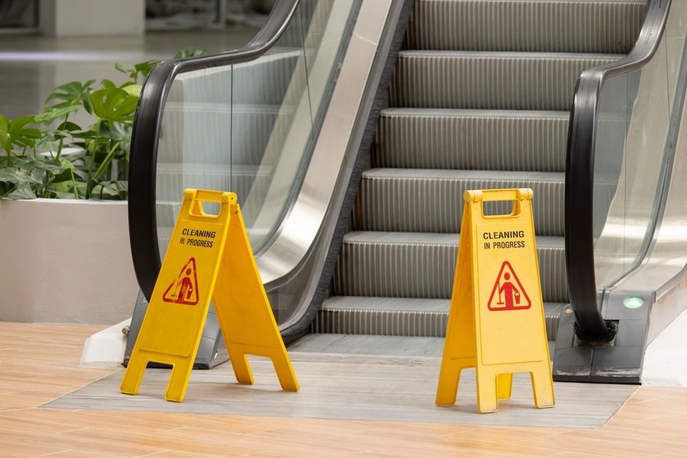Two yellow caution signs placed near an escalator warning of cleaning in progress, illustrating a property owner's duty of care in a Florida slip and fall claim