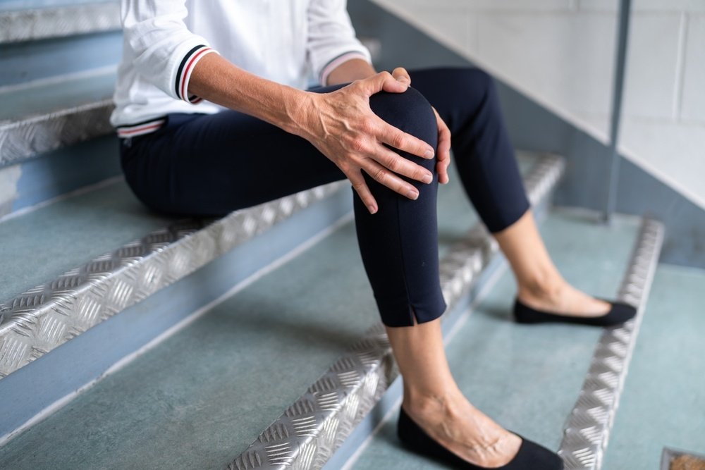 Injured person sitting on stairs holding their knee after a fall, representing the type of injury handled by a slip and fall lawyer in Florida